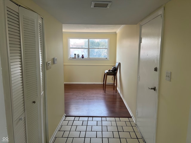 corridor featuring baseboards, tile patterned floors, and crown molding