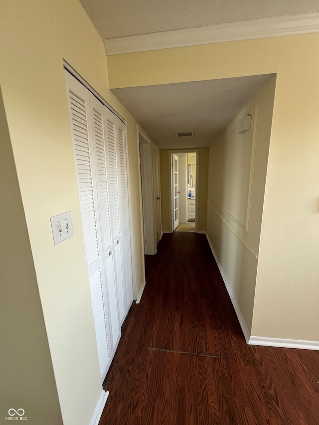 hallway with crown molding, wood finished floors, and baseboards