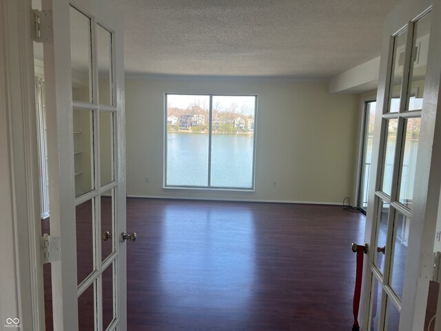 spare room with a wealth of natural light, french doors, dark wood finished floors, and a textured ceiling