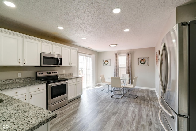 10597 Cyrus Dr, Indianapolis, IN 46231 - kitchen with appliances with stainless steel finishes, a textured ceiling, white cabinetry, recessed lighting, and light wood-style flooring