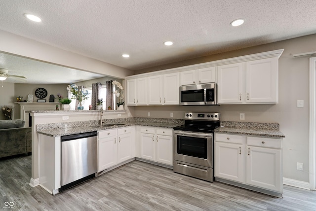 10597 Cyrus Dr, Indianapolis, IN 46231 - kitchen with stainless steel appliances, a sink, open floor plan, light wood finished floors, and white cabinetry