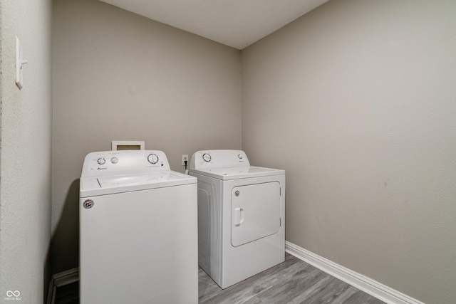 10597 Cyrus Dr, Indianapolis, IN 46231 - laundry room featuring separate washer and dryer, light wood-type flooring, and baseboards