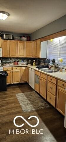 kitchen featuring dark wood-style floors, light countertops, decorative backsplash, dishwasher, and a sink
