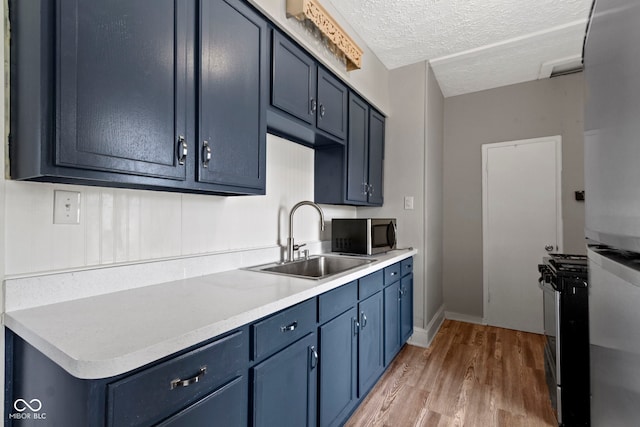 67 S 9th Ave, Beech Grove, IN 46107 - kitchen featuring blue cabinets, stainless steel appliances, a sink, and light wood-style floors