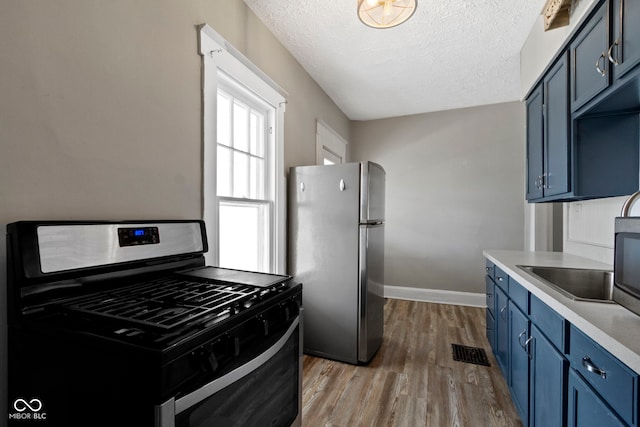 67 S 9th Ave, Beech Grove, IN 46107 - kitchen with blue cabinets, baseboards, wood finished floors, light countertops, and appliances with stainless steel finishes