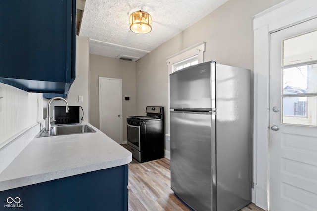 67 S 9th Ave, Beech Grove, IN 46107 - kitchen featuring blue cabinets, light wood-style floors, stainless steel appliances, and a sink