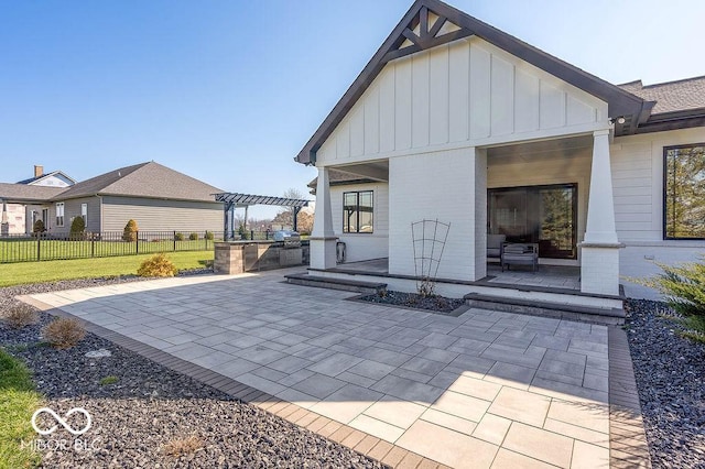rear view of house featuring board and batten siding, a pergola, a patio area, fence, and exterior kitchen