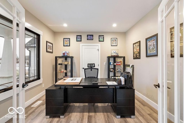 home office with light wood-style flooring, french doors, and baseboards