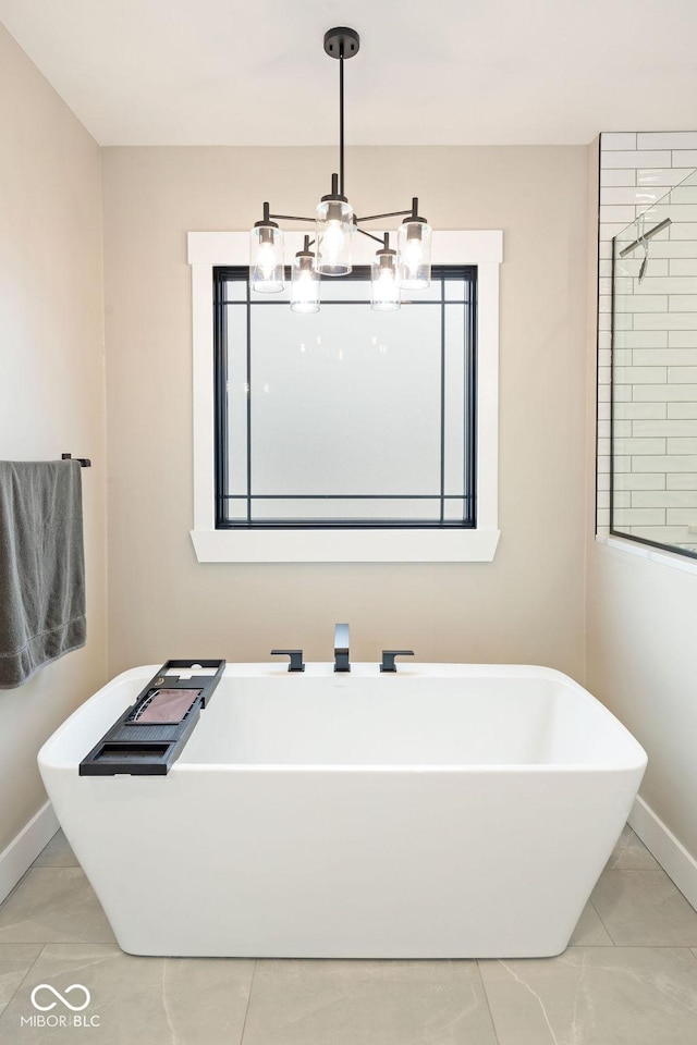bathroom with a freestanding tub, marble finish floor, baseboards, and an inviting chandelier