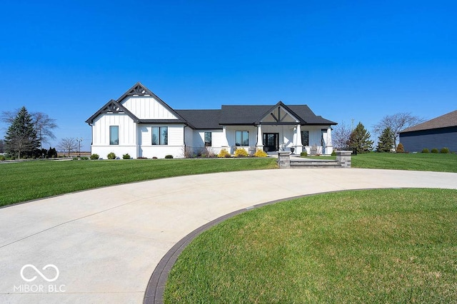 modern farmhouse with board and batten siding, covered porch, and a front yard