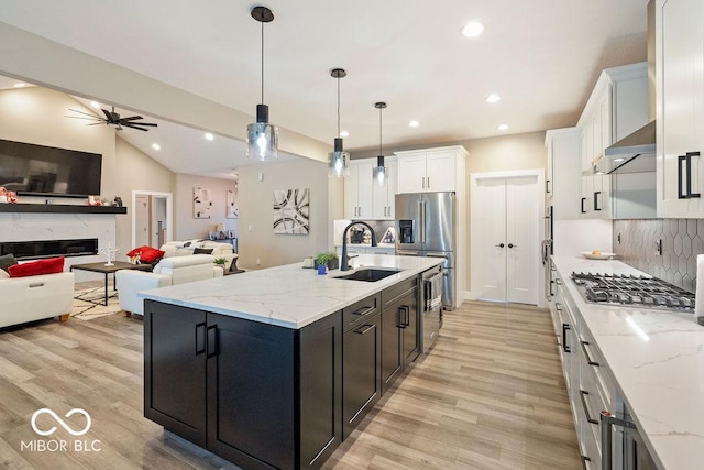 kitchen with white cabinets, appliances with stainless steel finishes, a sink, open floor plan, and extractor fan