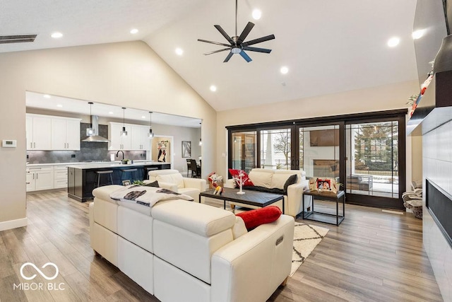 living room with recessed lighting, light wood-style flooring, visible vents, ceiling fan, and high vaulted ceiling