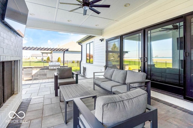 view of patio / terrace featuring an outdoor hangout area, a grill, a ceiling fan, fence, and exterior kitchen