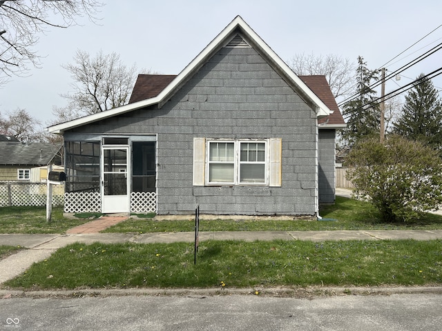 view of side of property with a lawn, a sunroom, and fence