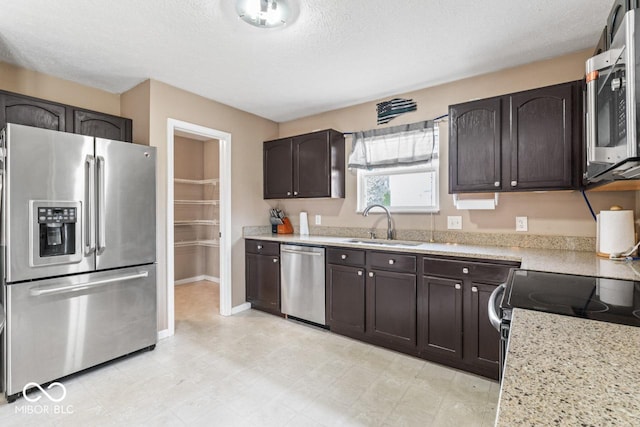 5817 Thompson Park Blvd, Indianapolis, IN 46237 - kitchen featuring a sink, appliances with stainless steel finishes, dark brown cabinetry, and a textured ceiling