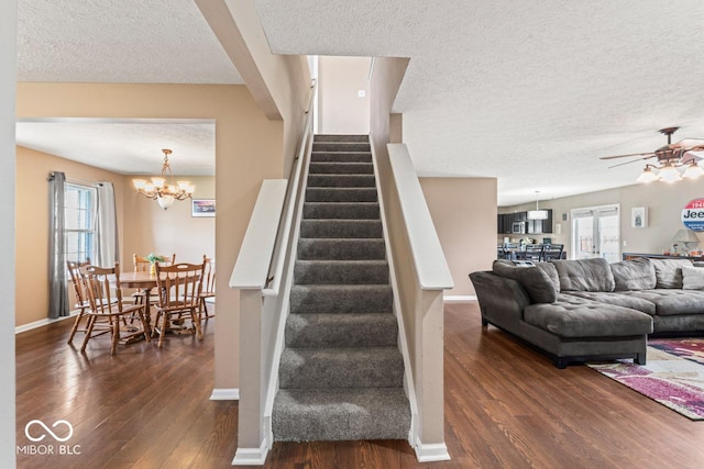 5817 Thompson Park Blvd, Indianapolis, IN 46237 - staircase featuring a textured ceiling, ceiling fan with notable chandelier, wood finished floors, and baseboards