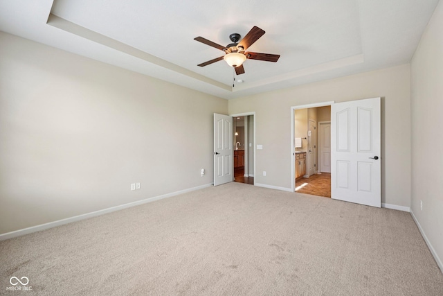 12907 Shiraz Ln, Fishers, IN 46037 - unfurnished bedroom with a tray ceiling, light carpet, baseboards, connected bathroom, and ceiling fan