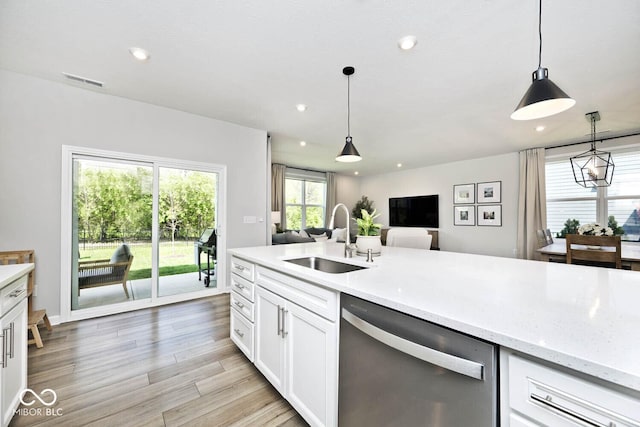 kitchen featuring recessed lighting, stainless steel dishwasher, a sink, open floor plan, and white cabinetry