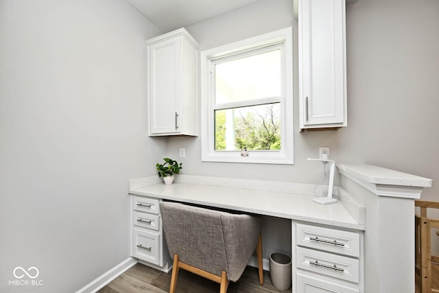 home office with baseboards, wood finished floors, and built in desk