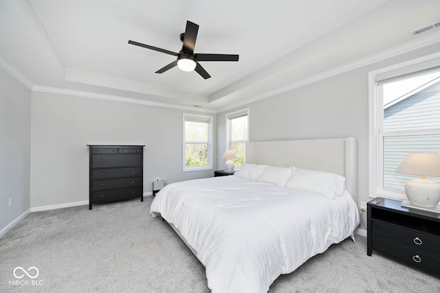 carpeted bedroom featuring crown molding, ceiling fan, a tray ceiling, baseboards, and visible vents