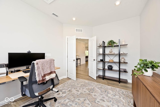 office area featuring light wood-type flooring, visible vents, and baseboards