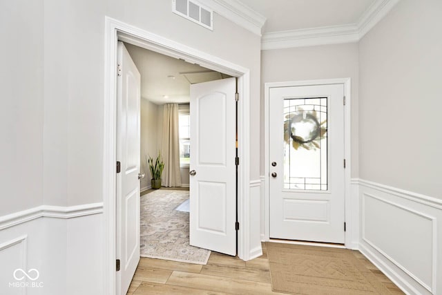 foyer with light wood finished floors, visible vents, crown molding, and a healthy amount of sunlight