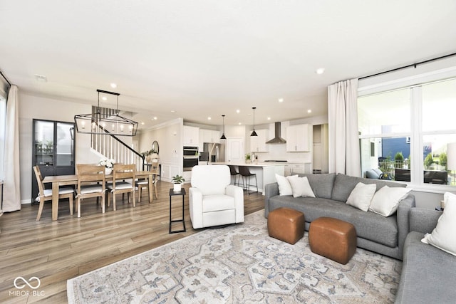 living area with light wood-type flooring, recessed lighting, and a notable chandelier