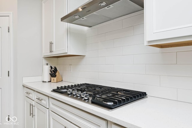 kitchen featuring backsplash, stainless steel gas cooktop, white cabinetry, and under cabinet range hood