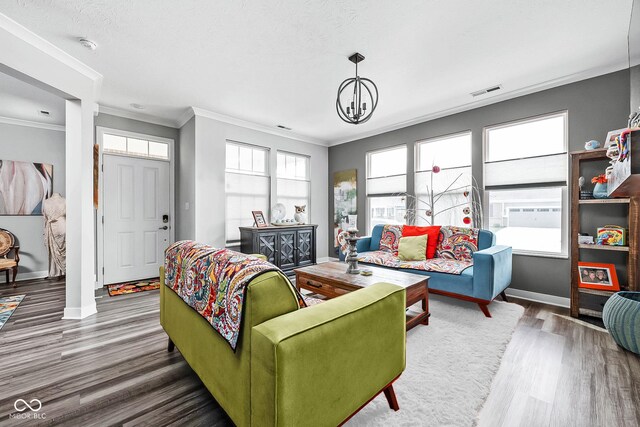 living room with wood finished floors, ornamental molding, baseboards, and a chandelier