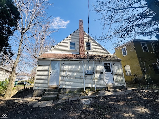 back of property with entry steps and a chimney