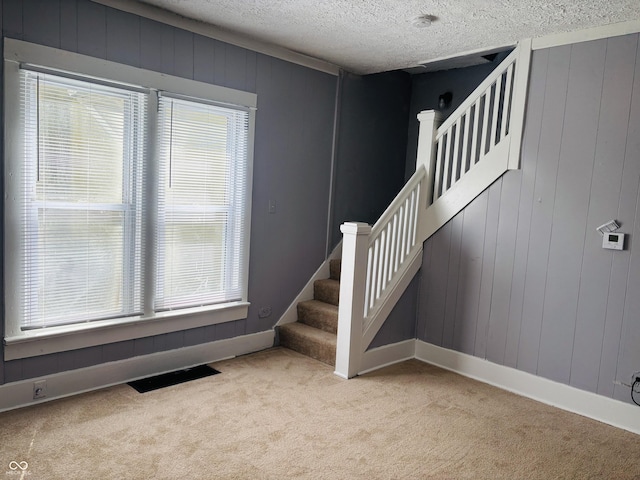 stairway featuring carpet floors, a wealth of natural light, visible vents, and baseboards