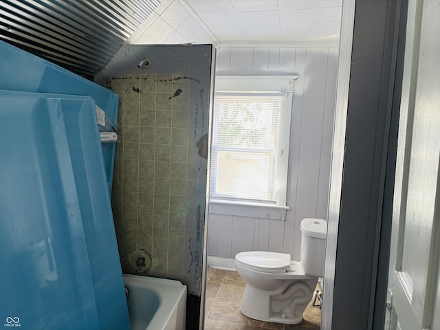 bathroom with a decorative wall, toilet, and tub / shower combination