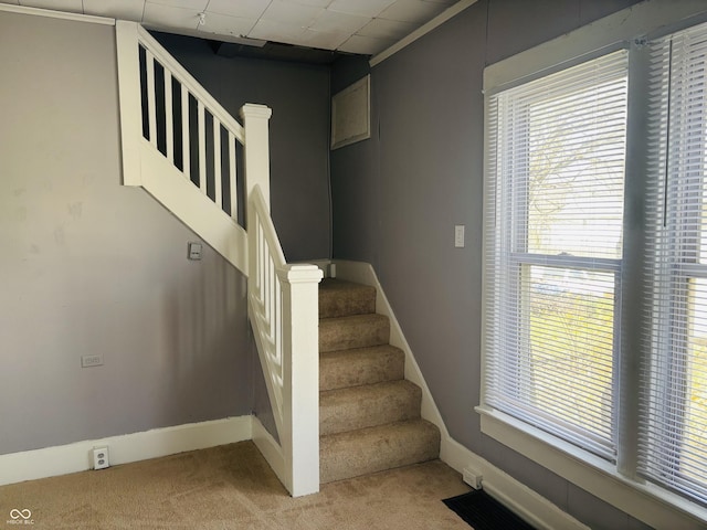 staircase with baseboards, plenty of natural light, and carpet floors
