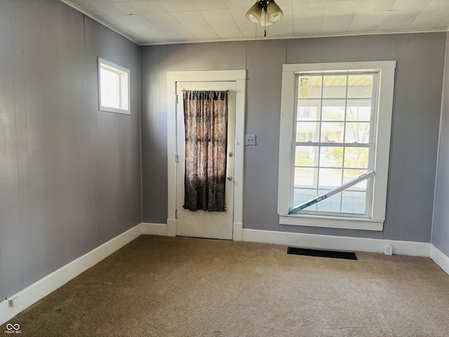 doorway to outside featuring carpet, visible vents, baseboards, and crown molding