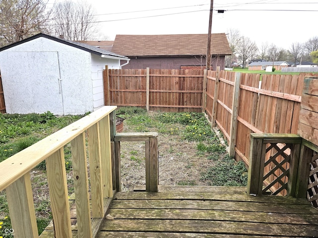 deck with a fenced backyard, a storage unit, and an outdoor structure