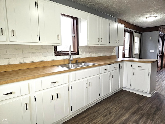 kitchen featuring white cabinets, a sink, dark wood-style flooring, a peninsula, and a textured ceiling
