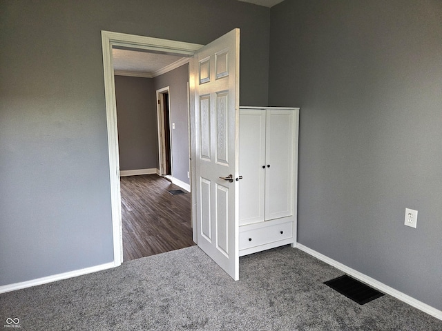 unfurnished room with crown molding, visible vents, baseboards, and carpet flooring