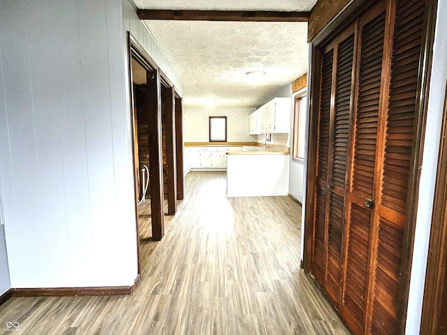 hallway with light wood-style floors and a textured ceiling