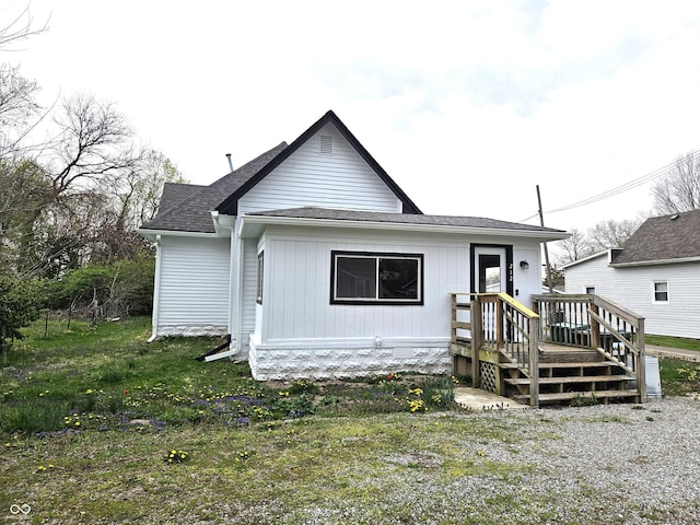 view of front facade with a front yard and a shingled roof