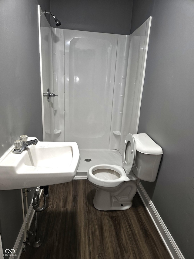 bathroom with toilet, baseboards, a stall shower, and wood finished floors