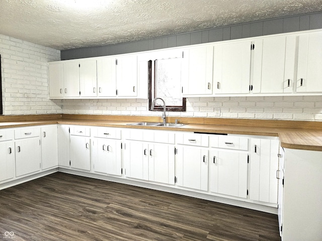 kitchen with a sink, white cabinets, a textured ceiling, and dark wood-type flooring
