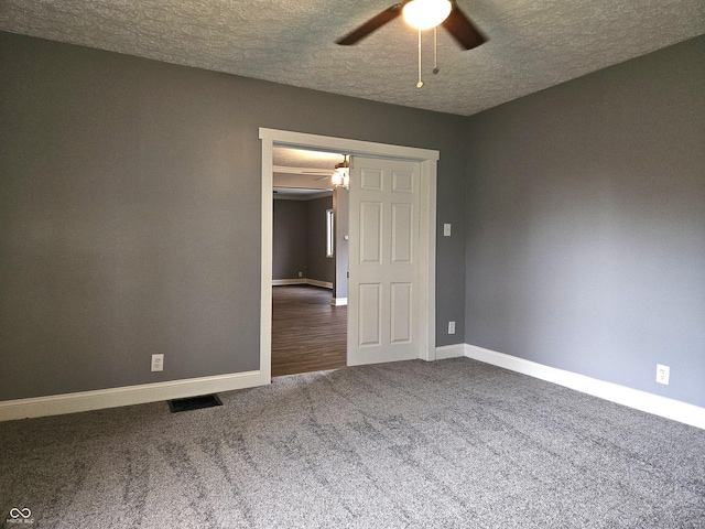 carpeted spare room featuring visible vents, ceiling fan, baseboards, and a textured ceiling