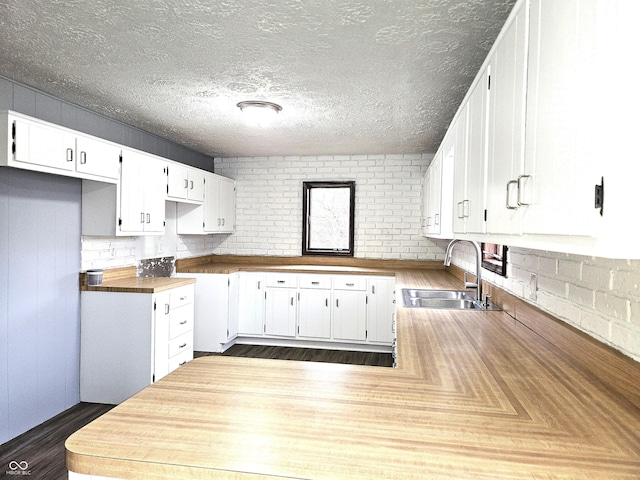kitchen with white cabinets, a peninsula, a sink, and dark wood finished floors