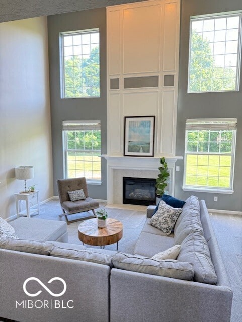 11648 Stickney Ct, Fishers, IN 46037 - living room featuring carpet floors, a glass covered fireplace, a towering ceiling, and baseboards