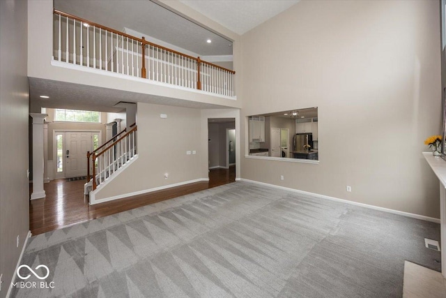 11648 Stickney Ct, Fishers, IN 46037 - unfurnished living room featuring a high ceiling, carpet, baseboards, stairs, and decorative columns