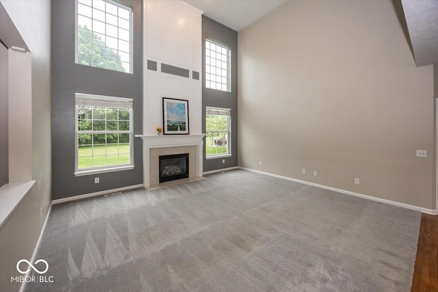 11648 Stickney Ct, Fishers, IN 46037 - unfurnished living room with high vaulted ceiling, baseboards, a high end fireplace, and light carpet