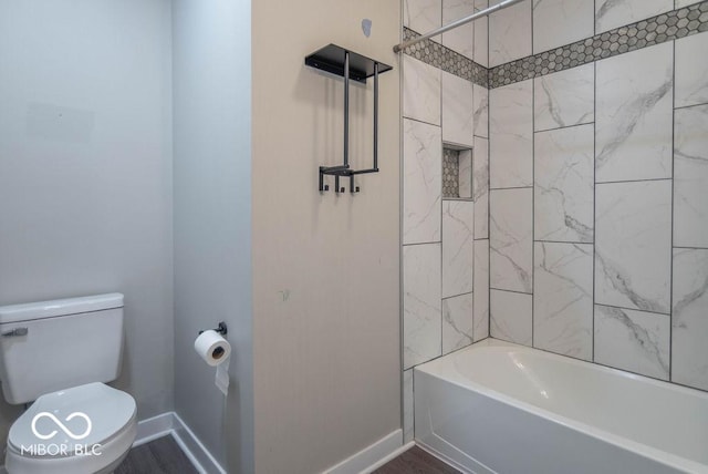 bathroom with baseboards, shower / bathing tub combination, and toilet