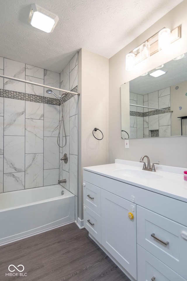 bathroom featuring a textured ceiling, bathing tub / shower combination, wood finished floors, and vanity