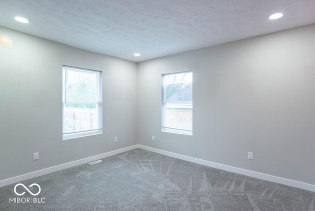 carpeted empty room featuring recessed lighting, baseboards, and a wealth of natural light