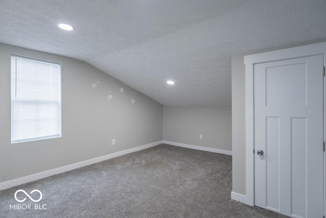bonus room with carpet flooring, a textured ceiling, vaulted ceiling, and baseboards